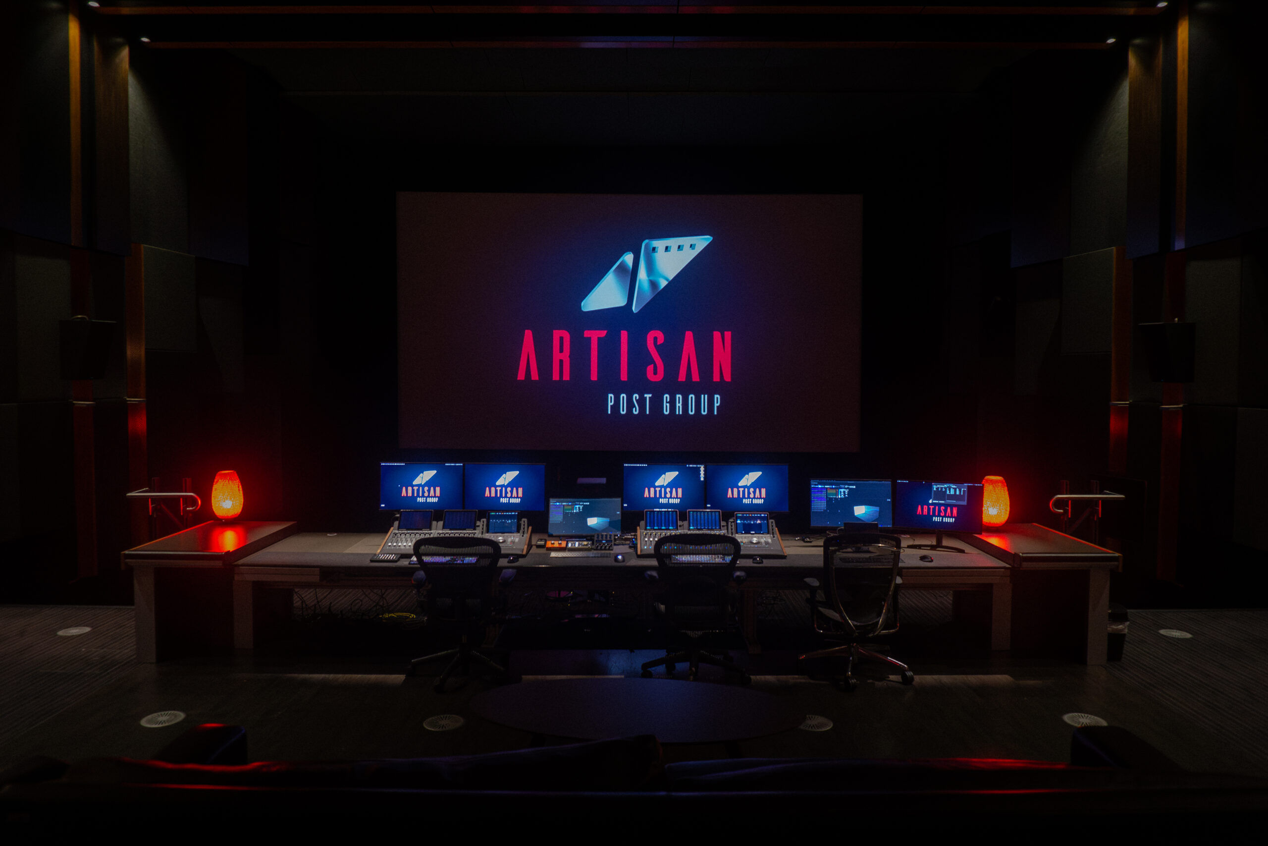 A mixing desk in front of a theatre screen, which reads Artisan Post Group